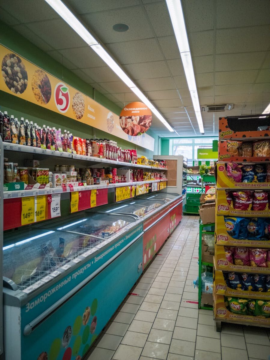 Explore a well-stocked aisle in a Russian supermarket. Frozen goods and snacks line the shelves.